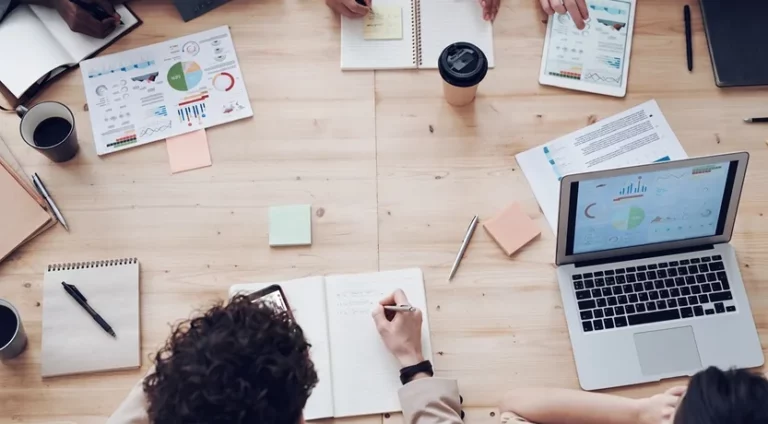 Tavolo visto dall'alto con grafici stampati, quaderni e un portatile, il lavoro di preparazione dei report