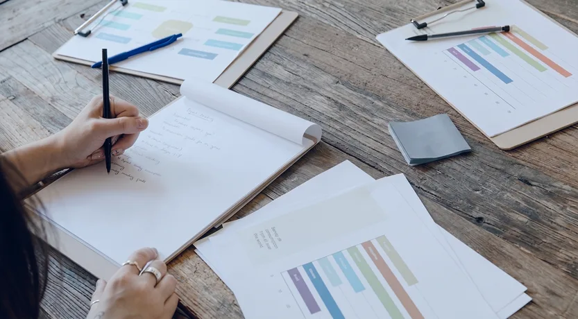 Appunti e grafici stampati sul tavolo durante il confronto dei costi tra Zoho One e Salesforce